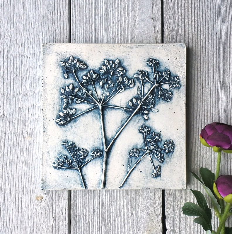 Blue coloured plaster cast tile with a raised image of Cow Parsley